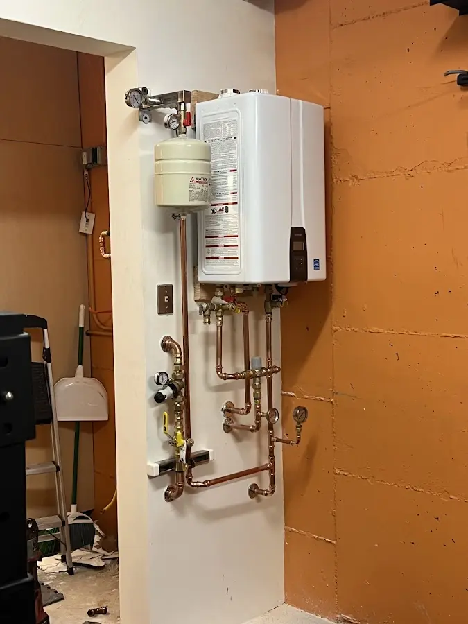 Plumbing technician inspecting water heater connections in Lawrence